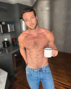 Foto colorida de Lucas Bissoli sem camisa segurando uma xícara de café - Metrópoles