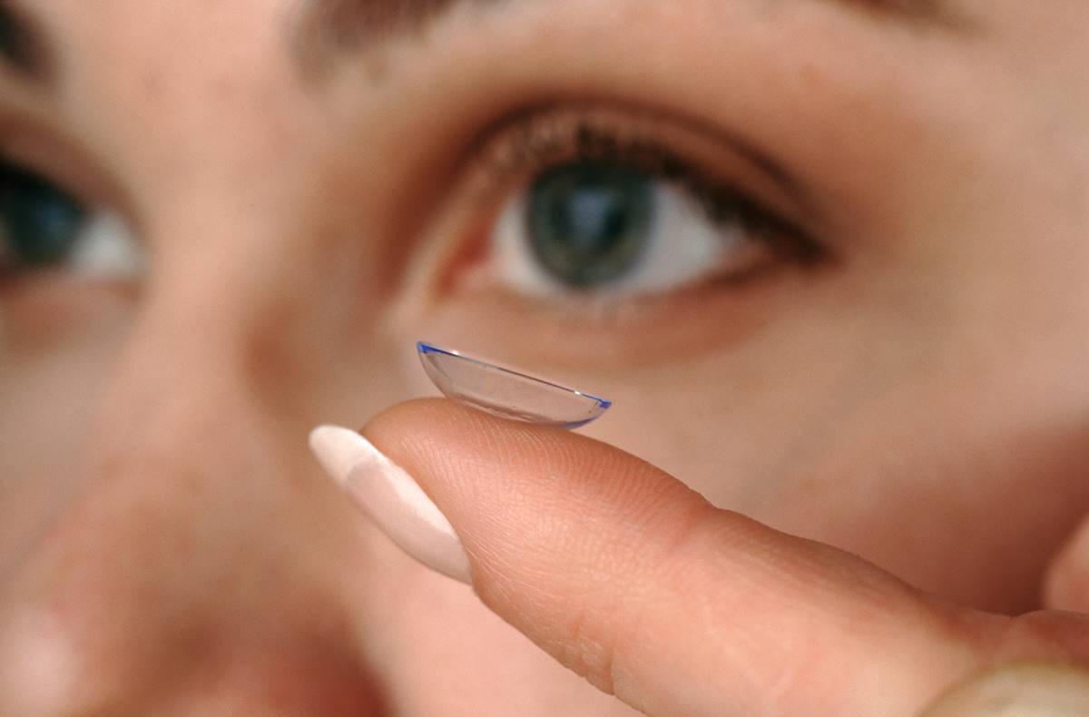 Olhos e um dedo segurando uma lente de contato