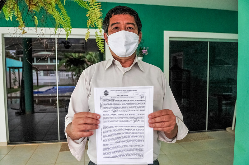 Foto colorida mostra homem segurando escritura de lote em Vicente Pires