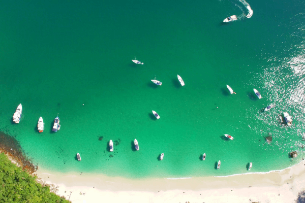 Imagem colorida de escunas e lanchas na praia de Jurubaíba em Angra dos Reis