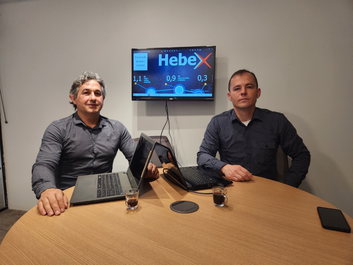 Fotografia colorida mostrando dois homens sentados em mesa-Metrópoles