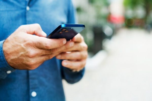 Foto colorida de homem branco segurando celular - Metrópoles