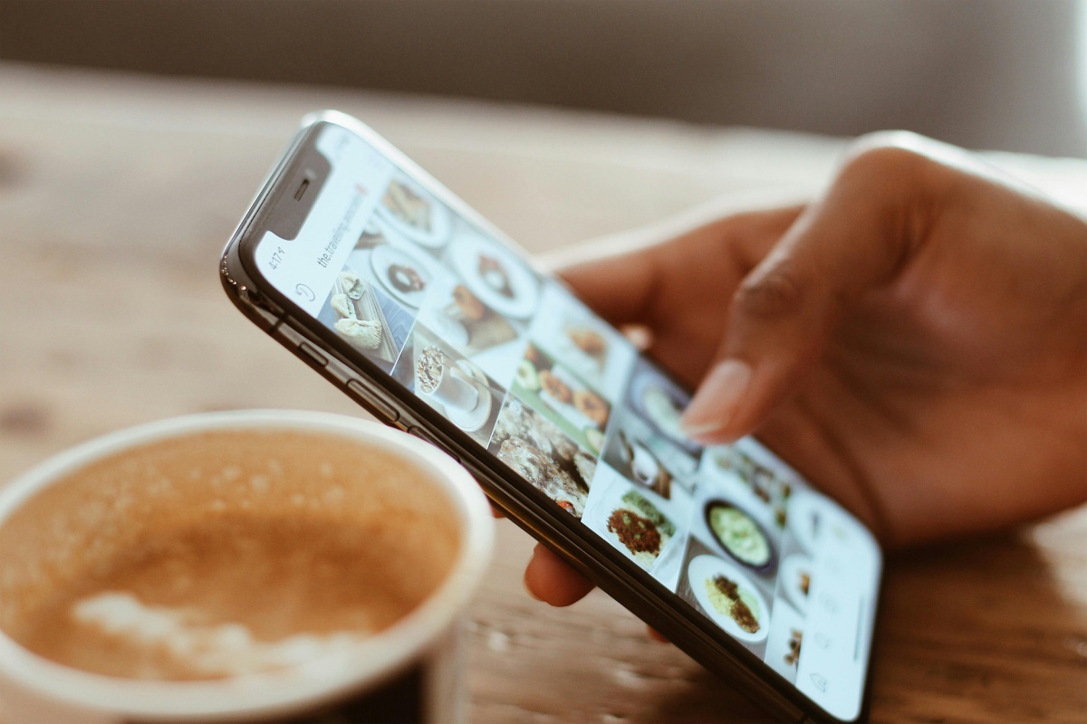 foto colorida de um celular em destaque com várias imagens e uma mão segurando - Metrópoles