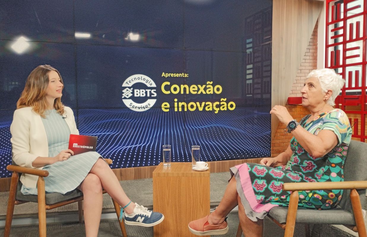 Fotografia colorida mostrando jornalista entrevistando mulher em estúdio-Metrópoles