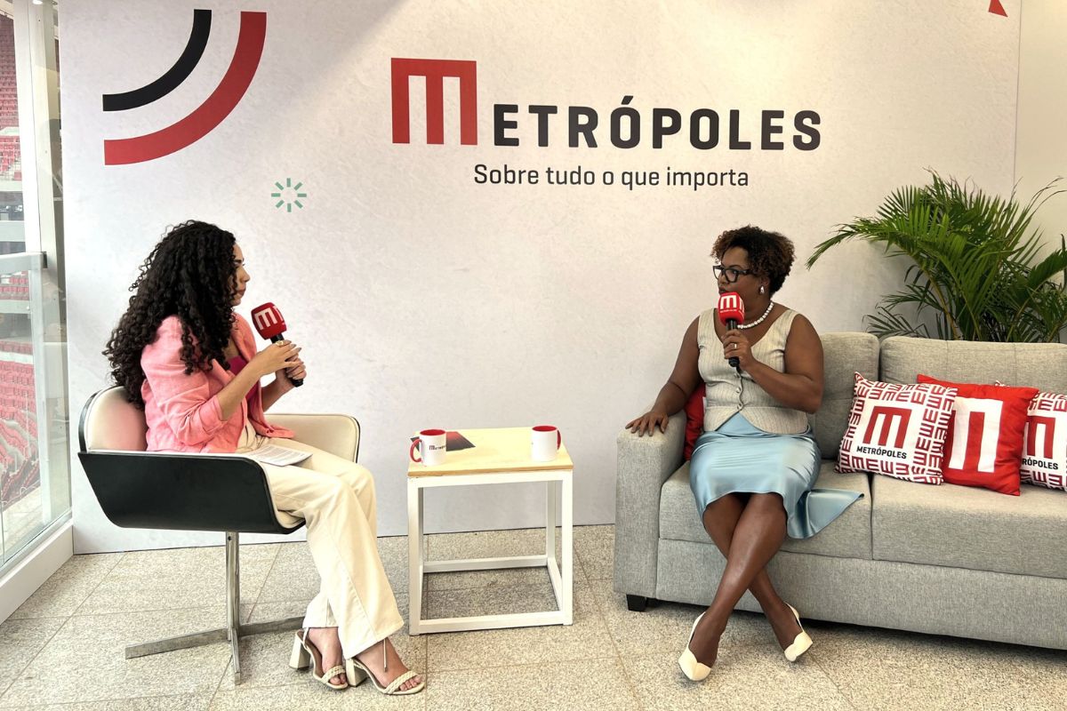 Fotografia colorida mostrando uma jornalista entrevistando uma mulher negra em estúdio-Metrópoles
