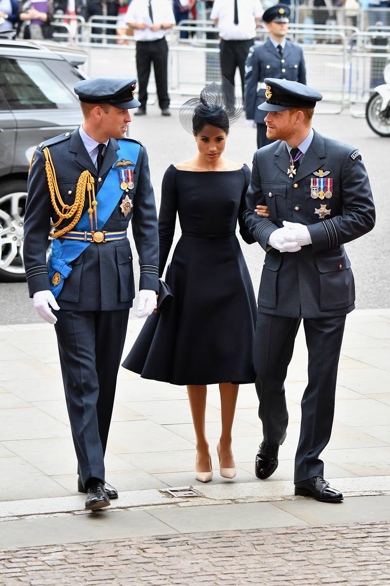 Foto colorida de dois homens com roupa militar. Entre eles, há uma mulher - Harry, Meghan e William - Metrópoles
