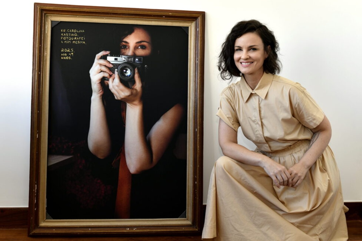 Imagem colorida de Carolina Kasting em frente a seu quadro