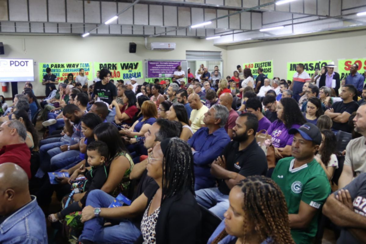 Foto colorida com dezenas de pessoas em uma sala de aula