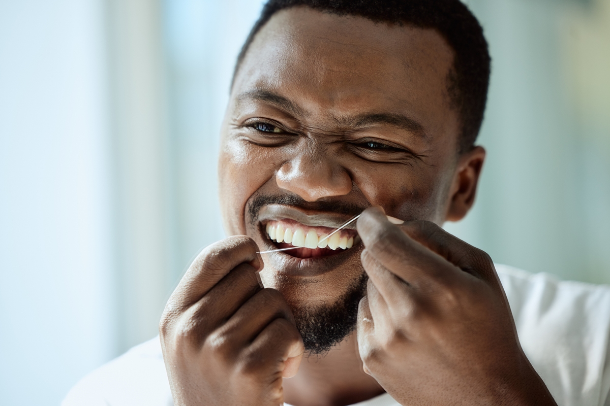 Homem fazendo limpeza de dentes com fio dental