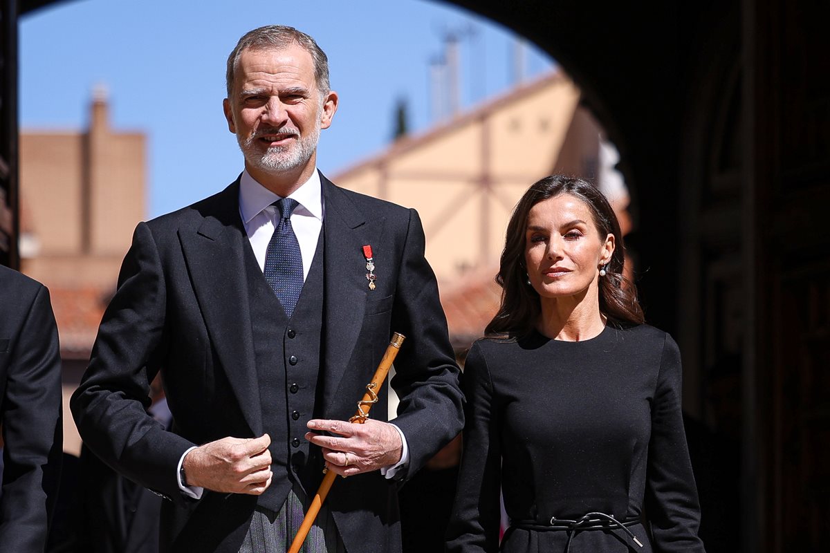 Foto colorida de homem arrumando o blazer preto. Ele está ao lado de mulher com roupas pretas - Metrópoles - realeza