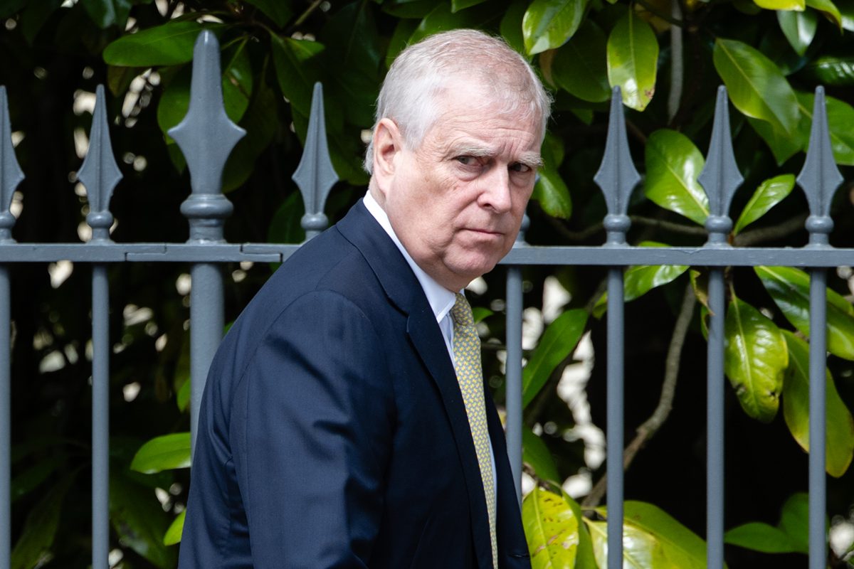Foto colorida de homem de terno, o ex-príncipe Andrew, caminhando próximo a portão - Metrópoles
