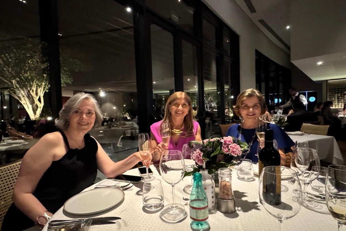 Foto colorida trio de amigas sentadas a mesa