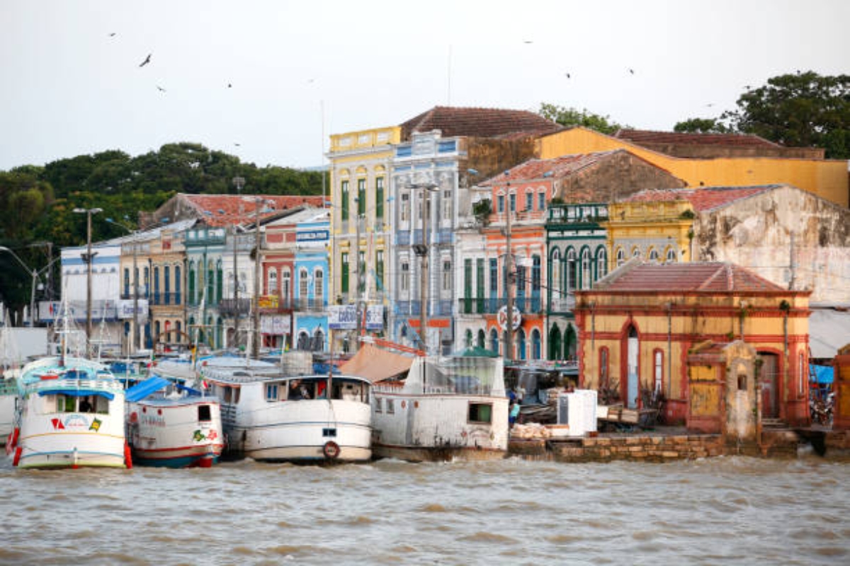 Vista panorâmica de Belém, com casas coloridas à beira do rio e pequenas embarcações ancoradas nas margens