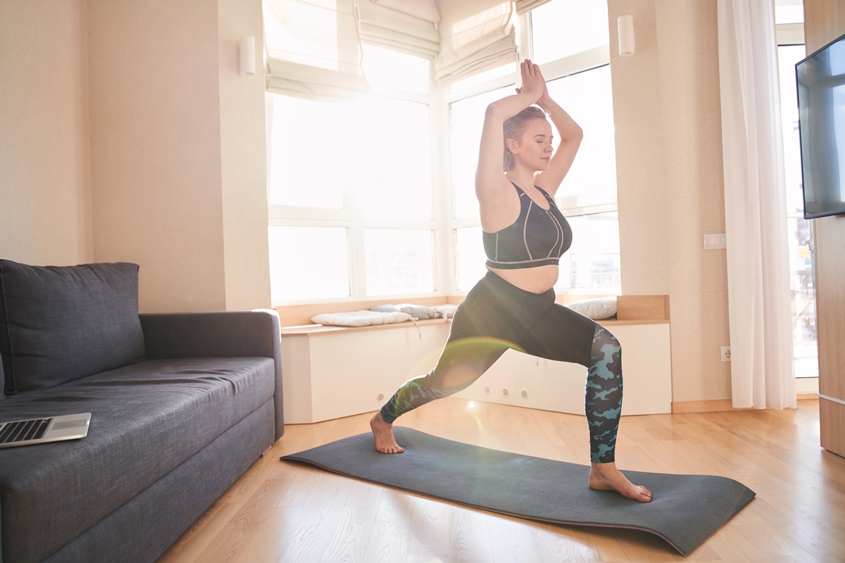 Mulher faz yoga em sala de casa - Metrópoles