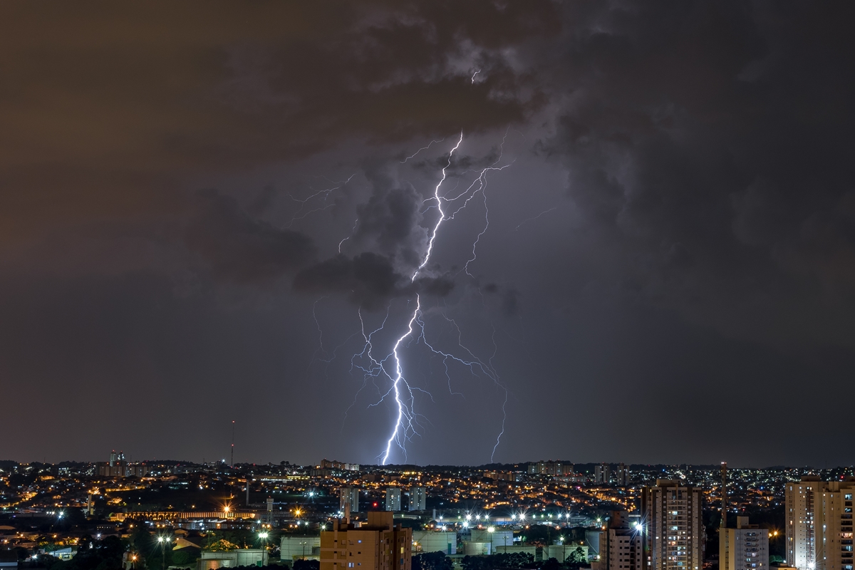 Foto colorida de cidade sob forte chuva de raio -Metrópoles.