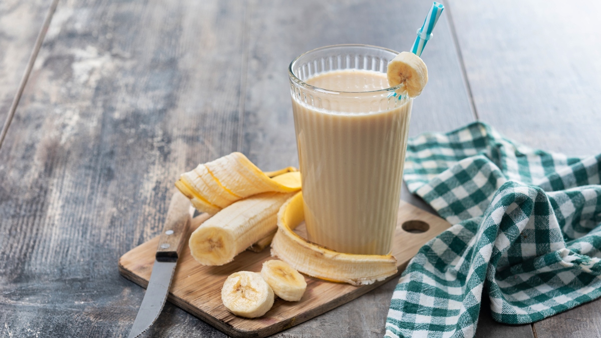 Foto colorida de copo contendo smoothie de banana sobre mesa