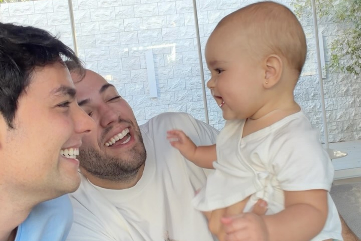 Imagem colorida do casal Lucas Bley e Lucas Rangel com a filha Mia - Metrópoles - Dia dos Pais