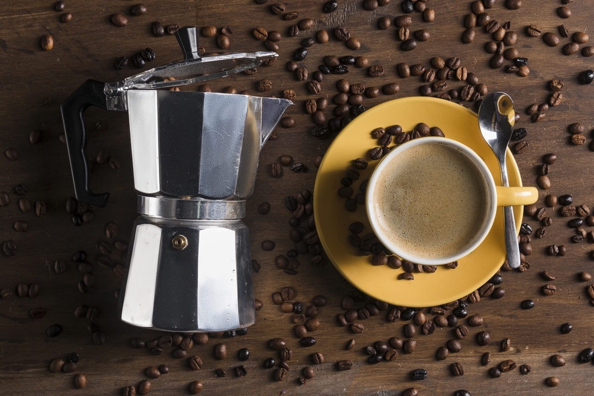 Foto colorida de cafeteira italiana e grãos de café