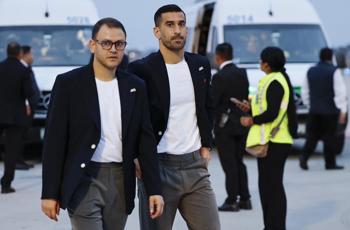 O capitão da seleção iraniana de futebol, Ehsan Hajisafi (C), caminha com um membro da comissão técnica após sua chegada ao Aeroporto Internacional de Tijuana usando um broche escrito #168
