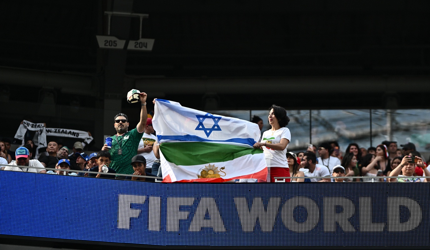 Torcedores do Irã posam para uma foto com uma bandeira iraniana pré-revolucionária unida a uma bandeira de Israel durante a partida do Grupo G da Copa do Mundo da FIFA 2026 entre Irã e Nova Zelândia no Estádio de Los Angeles 