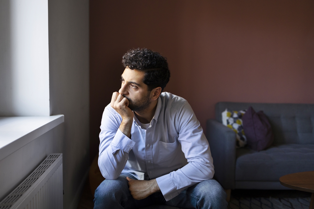 Foto colorida de homem sentado com expressão reflexiva