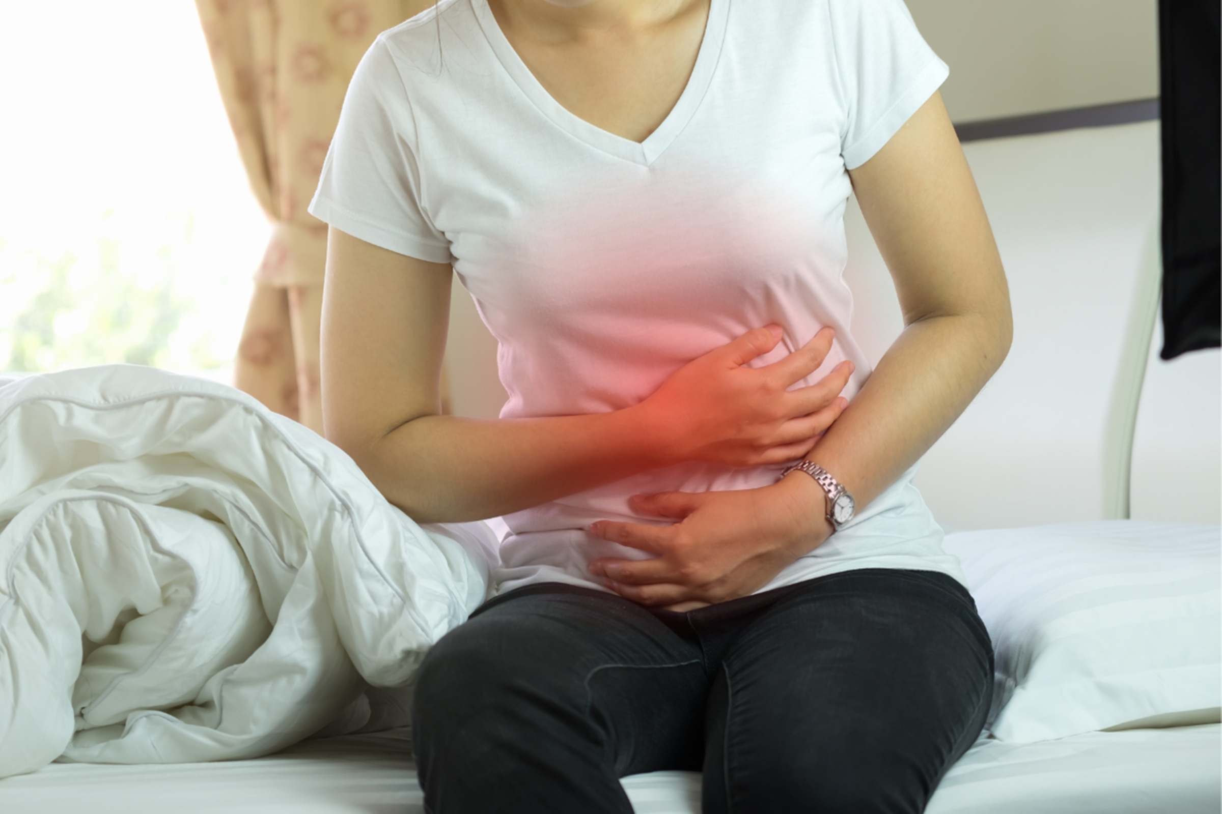 Mulher leva as mãos ao intestino como sinal de dor - e esse é um dos sintomas da Síndrome do Intestino Irritável