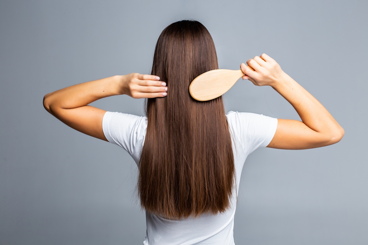 Mulher de costas penteando o cabelo