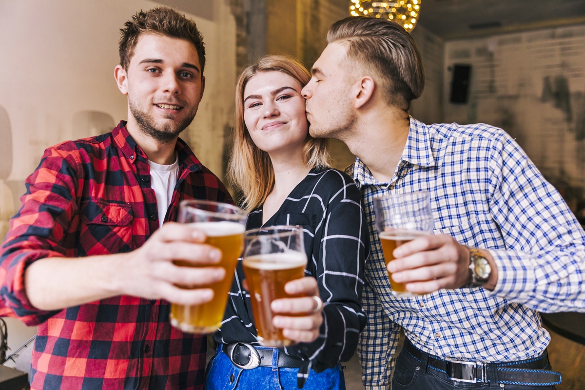 Foto colorida de mulher e dois homens bebendo cerveja