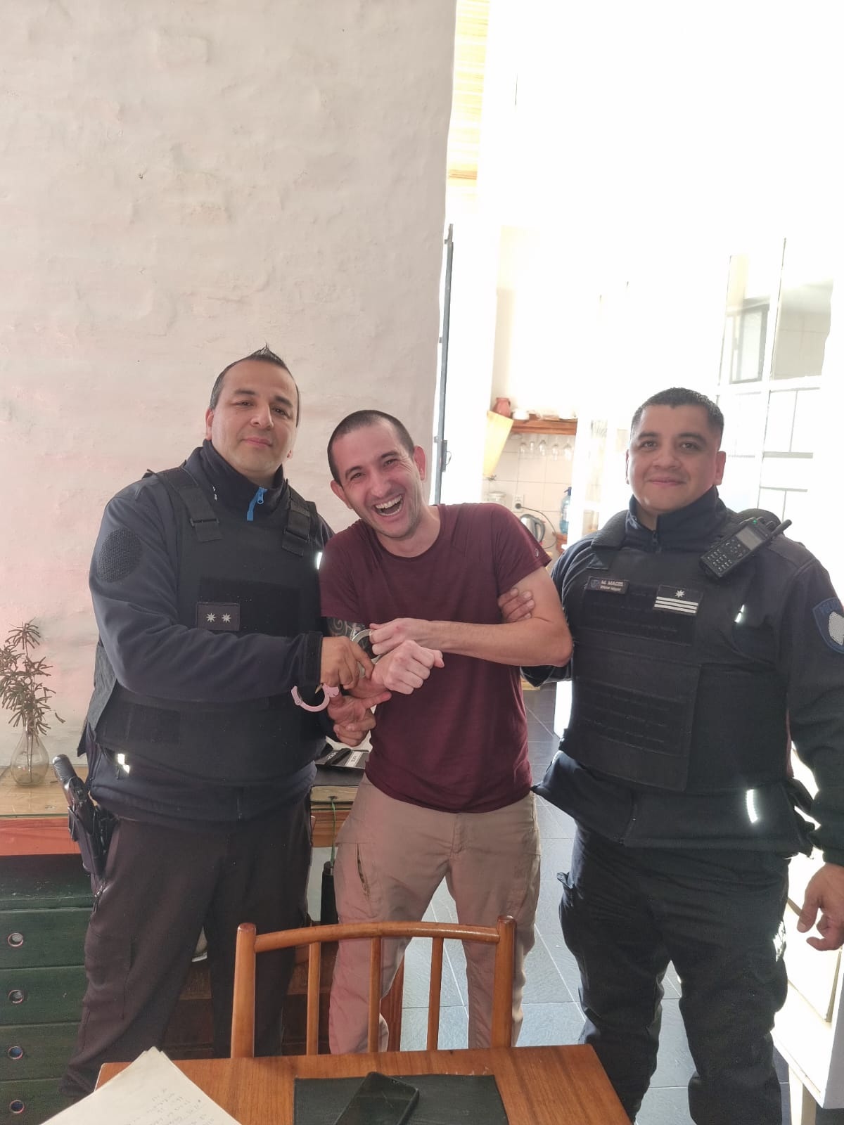Wellington Firmino, condenado pelos ataques aos Três Poderes, posa para foto com algemas ao lado de policiais da Argentina que verificam porque ele descumpriu ordem de prisão domiciliar e trocou de casa.
