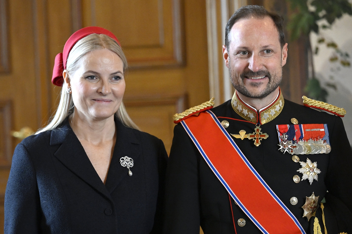 Foto colorida de mulher loira com roupa preta ao lado de homem com traje militar - Metrópoles