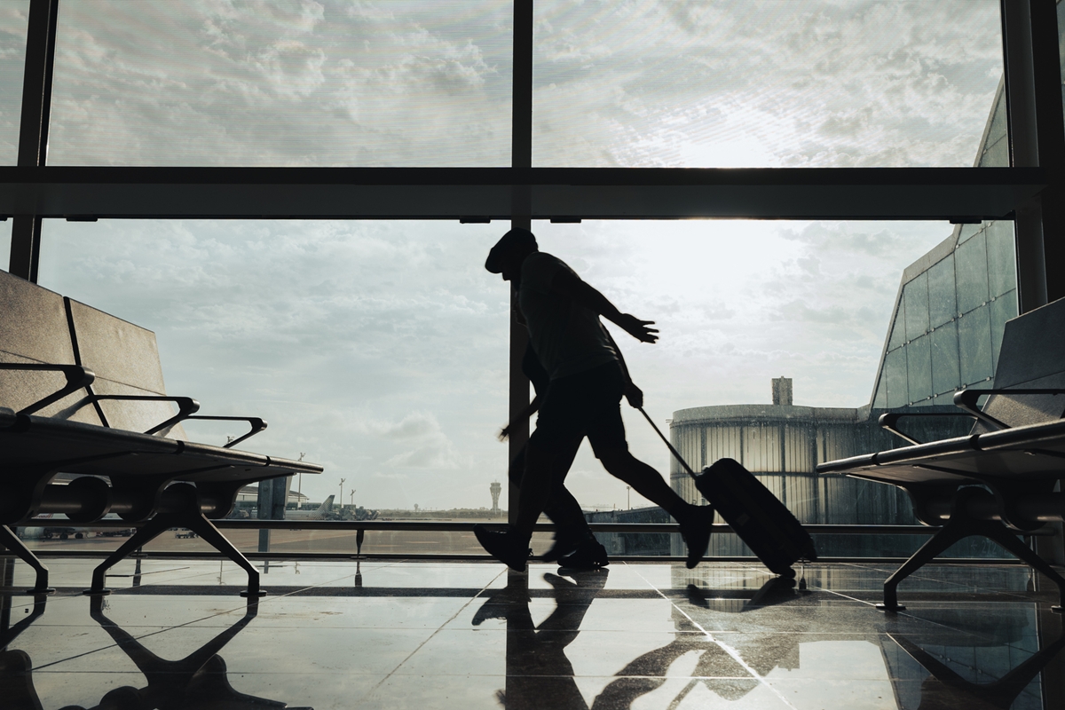 Foto colorida de homem correndo em aeroporto - Metrópoles