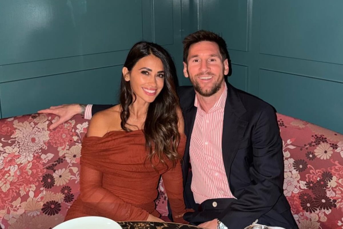Foto colorida de mulher e homem posando para foto. Eles estão sentados em um sofá cor-de-rosa - Metrópoles