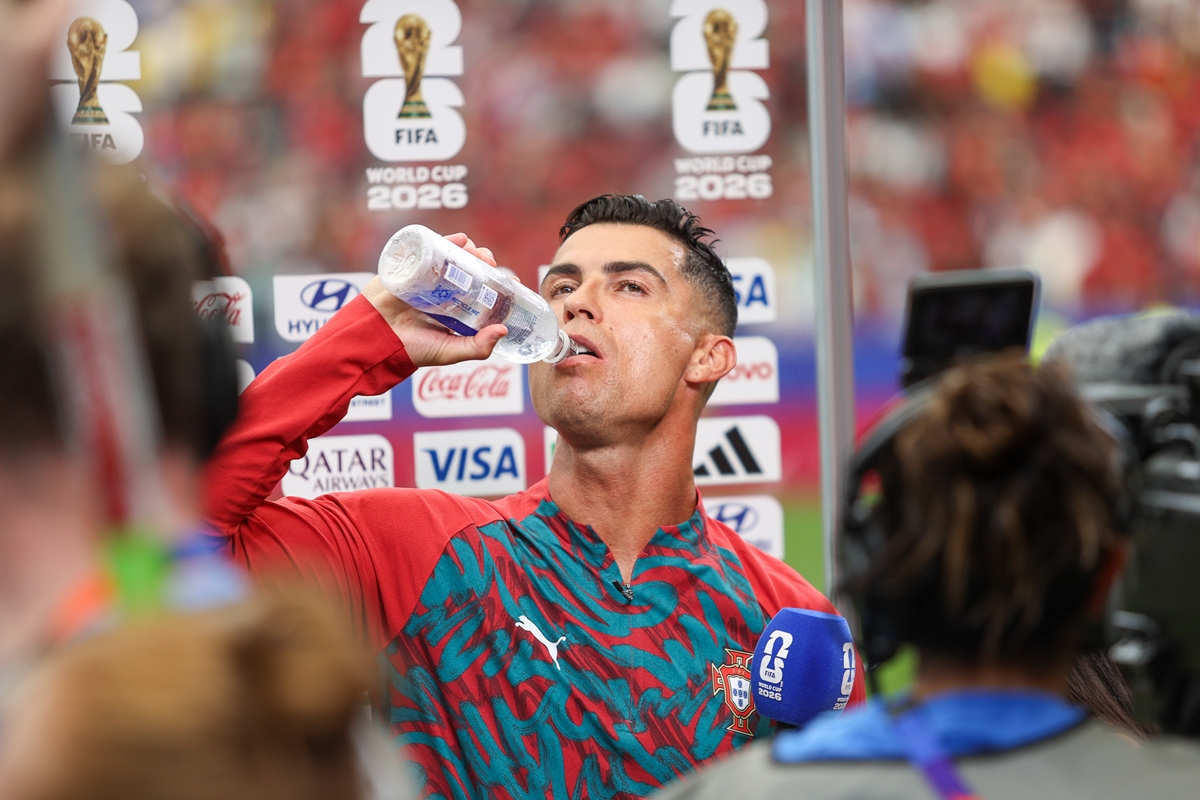 Foto colorida de homem com o uniforme da Seleção de Portugal tomando água - Metrópoles