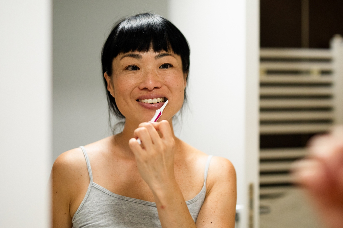 Foto colorida de mulher escovando os dentes - Metrópoles