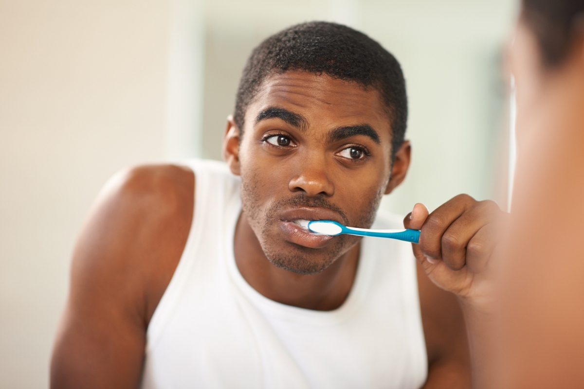 Foto colorida de homem escovando os dentes - Metrópoles
