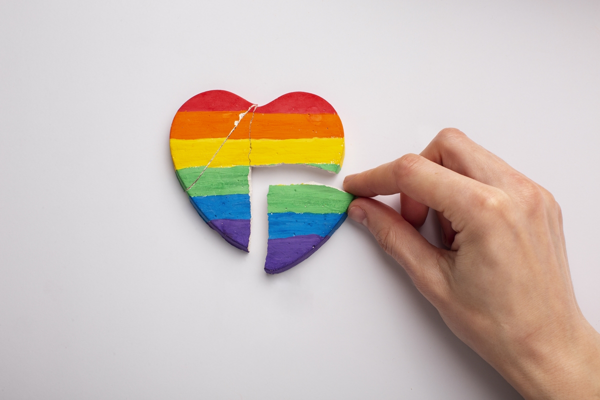 Imagem colorida de um coração quebrado com a bandeira LGBTQIAP+