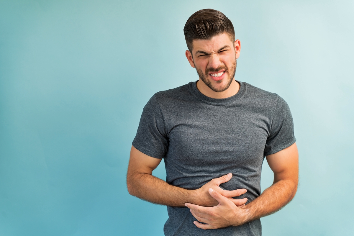 Foto colorida de homem com mão na barriga