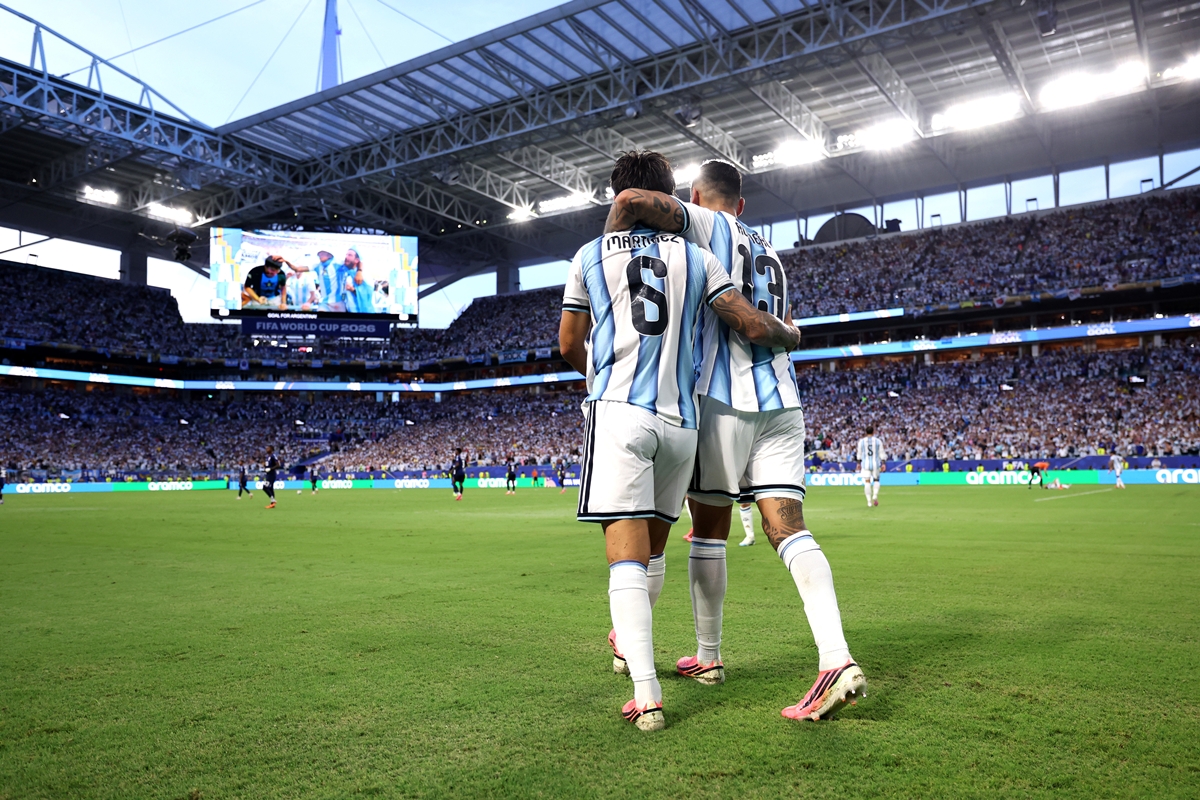 Foto colorida de dois jogadores da Argentina se abraçando em jogo de futebol - Metrópoles