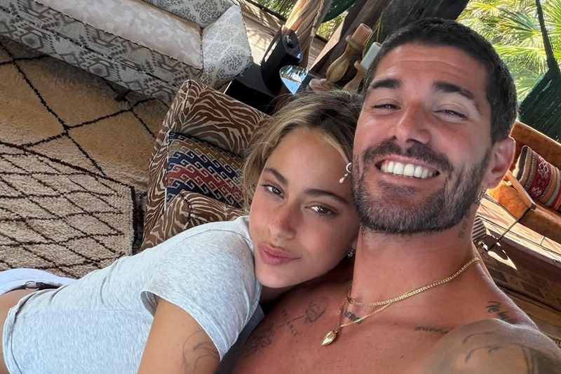 Foto colorida de mulher e homem abraçados e posando para selfie - Metrópoles