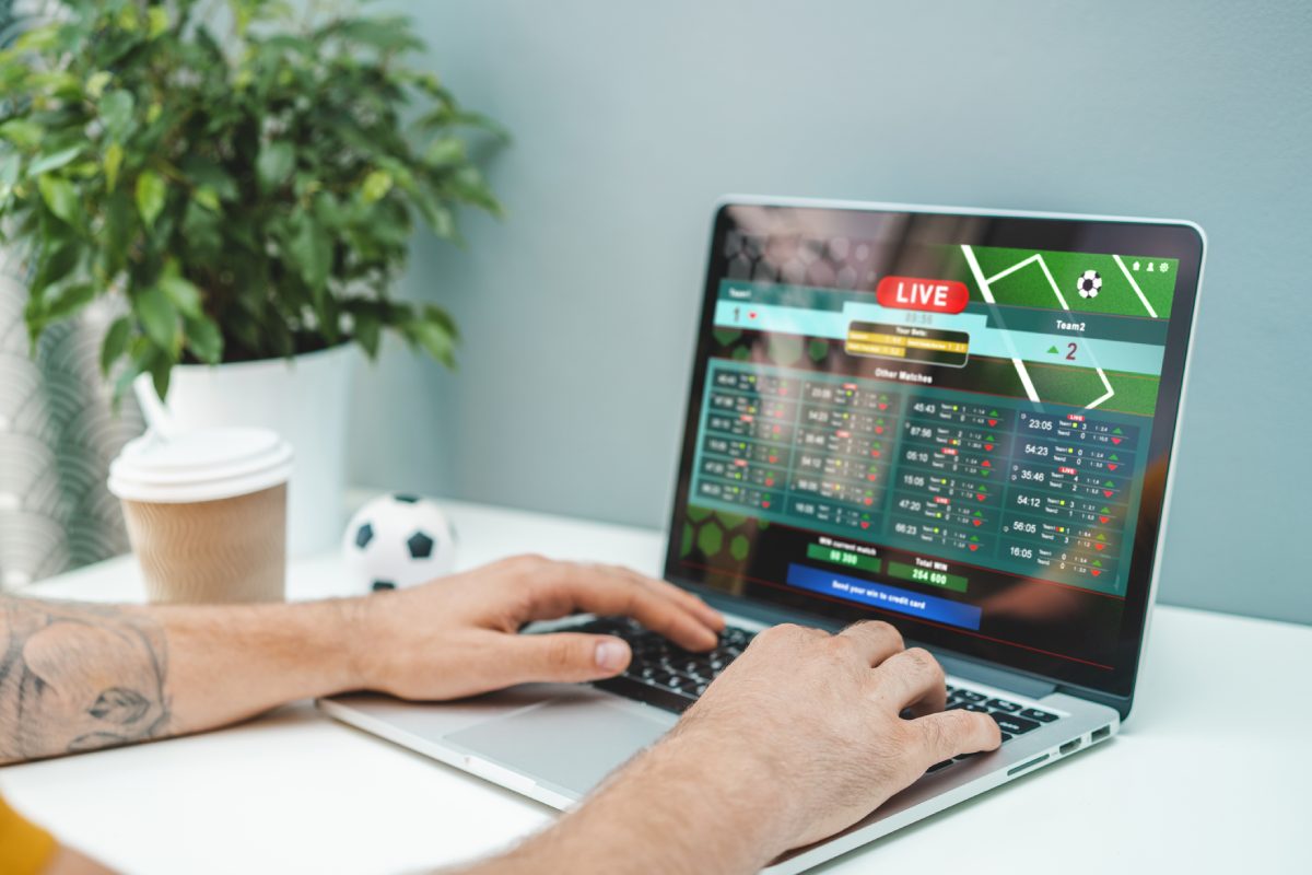 Pessoa analisa no computador regras de rollover em apostas esportivas