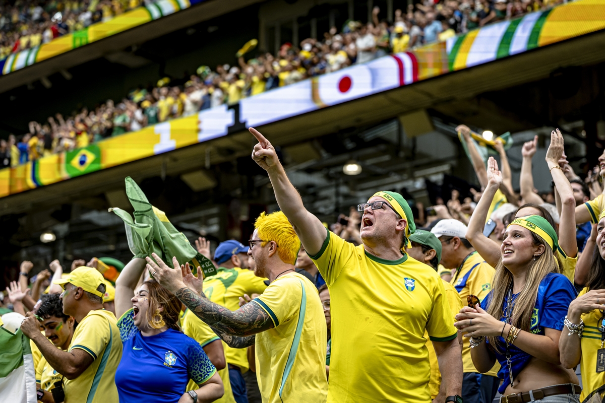Foto colorida de grupo de pessoas com a blusa da Seleção Brasileira em arquibancada - Metrópoles