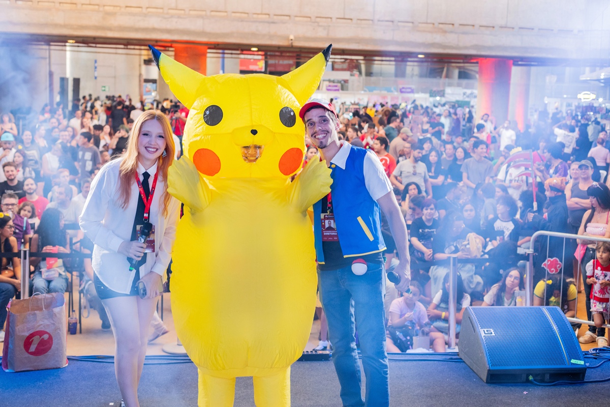 foto colorida de tres pessoas em cima de palco e multidão ao fundo - metrópoles