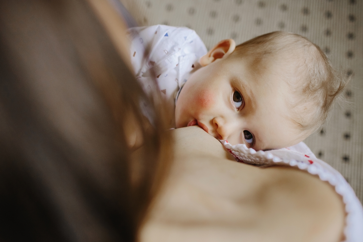 Foto colorida de mãe amamentando seu bebê - Metrópoles.