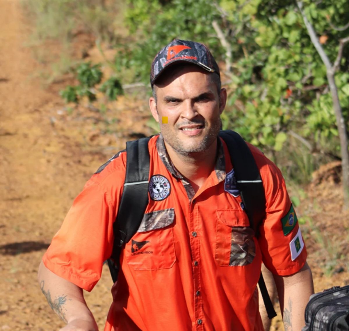 homem de boné e camisa laranja fazendo caminhada
