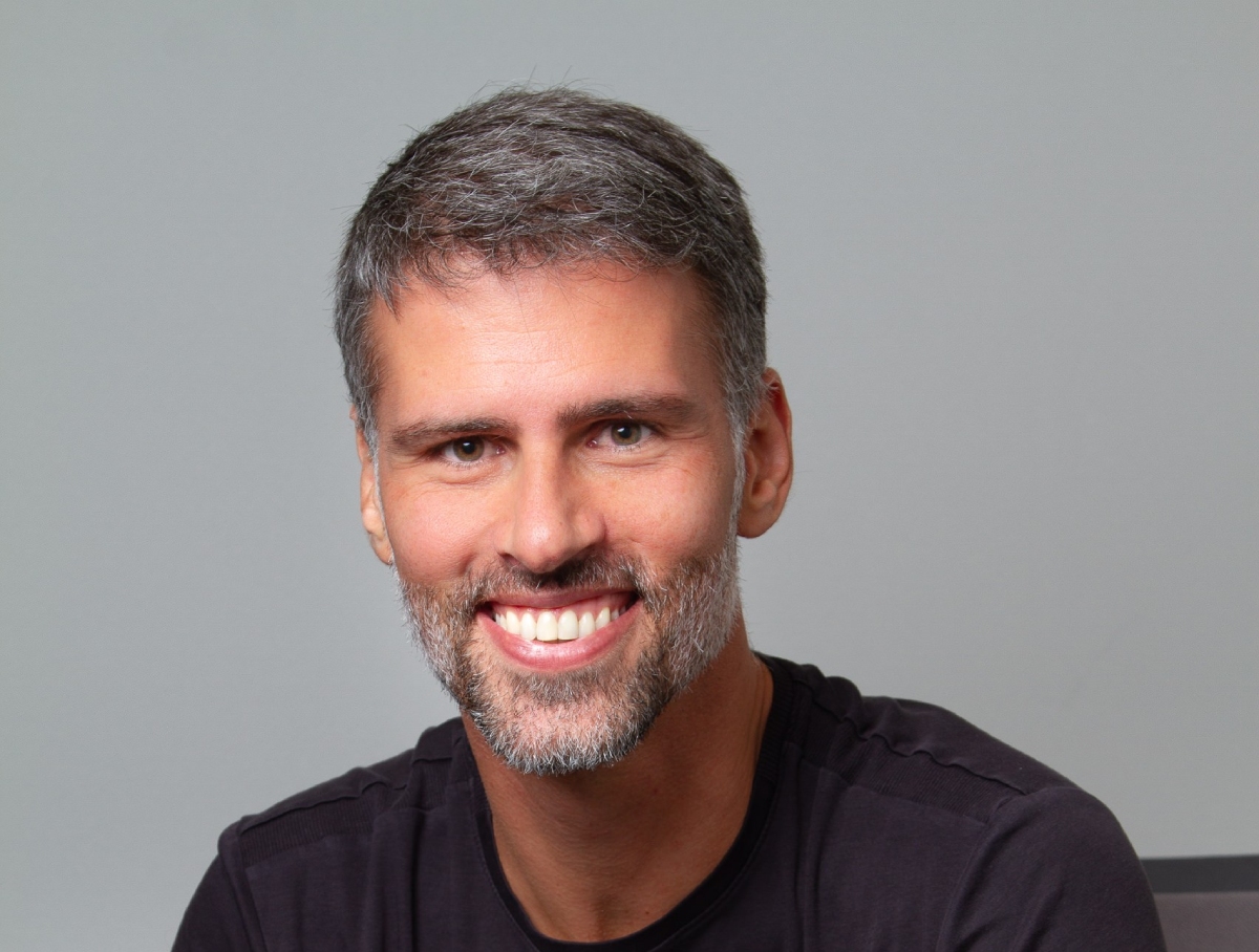 Retrato de Gustavo Almeida, diretor executivo da Fitness Brasil, sorrindo e olhando para a câmera. Ele aparece em primeiro plano, com fundo neutro.