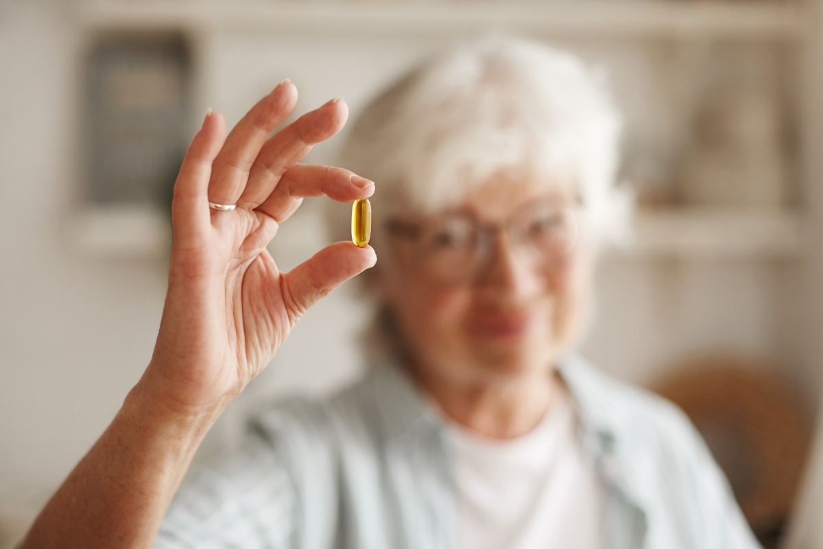 Imagem de uma idosa segurando uma pílula de vitamina b12 - Metrópoles