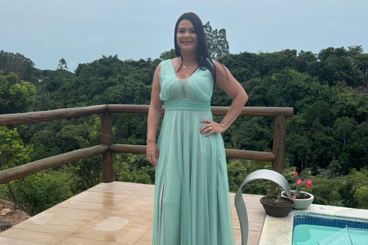 Foto colorida de mulher com vestido de cor azul claro em abiente aberto ao lado de uma pscina - Metrópoles.