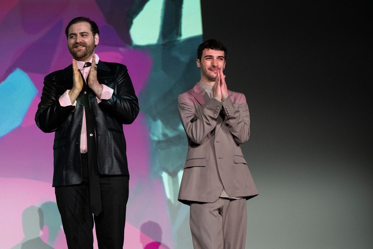 Foto colorida de Márcio Picoli e Victor Di Marco no palco do Festival de Veneza