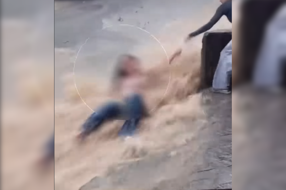 Jovem é resgatada após ser arrastada por enxurrada na rua e parar em poste