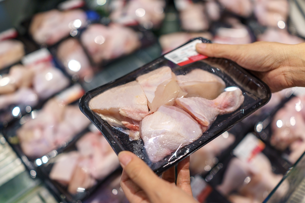 Foto colorida de mãos segurando uma bandeja de frango - Metrópoles